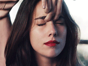 A gif of Eleanora from Skam Italy. Her left arm is raised up with her hand in front of her face and her eyes are closed. Her pointer and middle fingers are on either side of her nose bridge, slightly below her eyebrows. Her ring finger is bent, touching her forehead, and her thumb and pinkie finger are sticking outwards. She is wearing a light brown long-sleeved shirt and has red lipstick and shoulder-lenght dark brown hair.